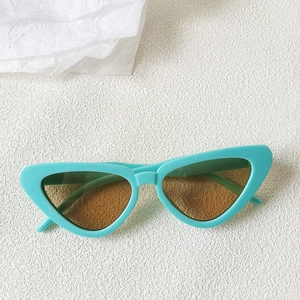 Close-up of mint green cat-eye sunglasses with brown lenses on a white textured surface