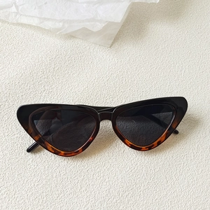 Detail of tortoise shell cat eye sunglasses with dark lenses on a minimalist background