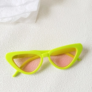 Detail of neon green cat-eye sunglasses with translucent pink lenses on a white background