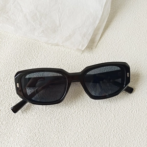 Détail de lunettes de soleil rectangulaires noires avec clous en métal argenté