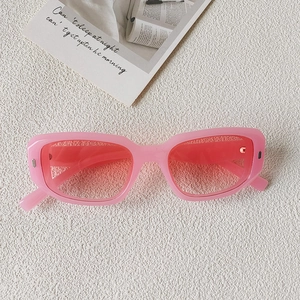 Gros plan de lunettes de soleil rectangulaires roses sur une surface texturée blanche
