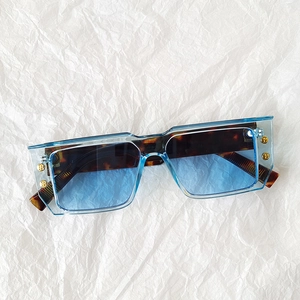 Detail of square sunglasses with blue transparent frame and golden B logo on temples