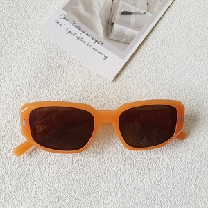 Détail de lunettes de soleil carrées orange rétro avec rivets métalliques sur fond blanc