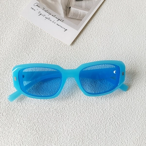 Détail de lunettes de soleil carrées bleues avec rivets rétro sur fond blanc texturé