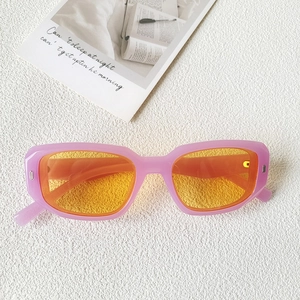 Détail de lunettes de soleil roses rectangulaires avec verres orange et rivets
