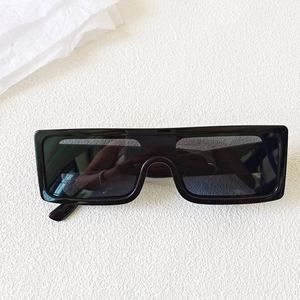 Flat lay of retro black oversized rectangle one-piece lens sunglasses on beige background