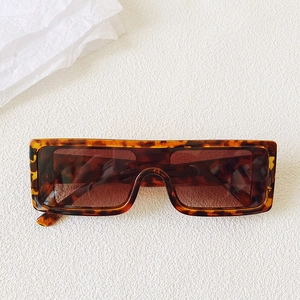 Detail view of tortoiseshell rectangle sunglasses with thick frame and dark brown lenses