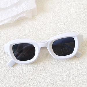 Top view of thick white plastic cat-eye sunglasses with dark grey UV lenses on white background
