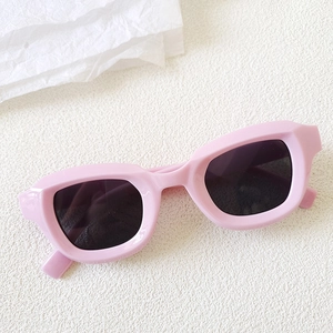 Flat lay of pink bubble-style sunglasses on white textured surface with aesthetic props