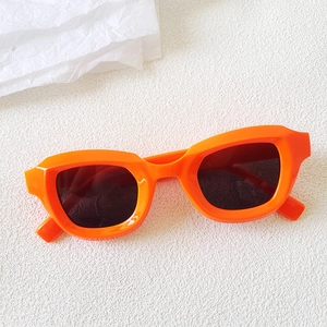 Detail of bright orange bubble frame cat eye sunglasses with dark lenses on white background