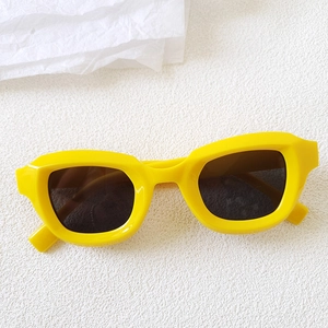 Detail of vibrant yellow chunky rectangle cat-eye sunglasses with dark tinted lenses