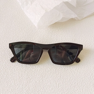Macro shot of stylish thick-framed rectangular sunglasses in a dark glossy finish