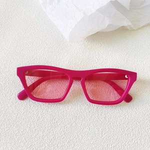 Detail of trendy rose pink cat-eye sunglasses with translucent lenses on white textured surface