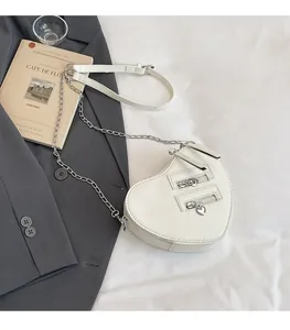 Dettaglio della borsa a tracolla bianca a forma di cuore con cerniere e catena