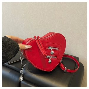 Dettaglio borsa a tracolla a forma di cuore rosso con ciondoli a cuore in argento sulla zip