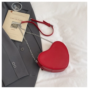 Dettaglio della borsa rossa a forma di cuore con catena d'argento su fondo bianco