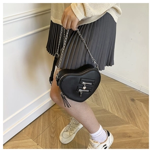 Dettaglio della borsa a tracolla a cuore con cerniere argentate e nappe alla moda