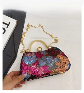Detail of sequin floral evening bag featuring gold metal handle and pearl clasp