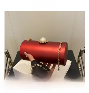 Détail de pochette de soirée cylindrique rouge avec fermoir perle et chaîne dorée