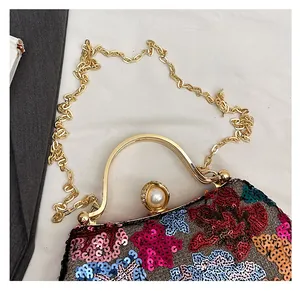 Detail of evening clutch featuring vibrant sequins, gold handle, and large pearl clasp