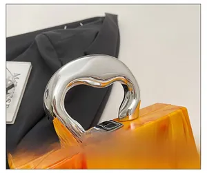 Macro detail of orange marble acrylic clutch with chunky silver metal handle and clasp