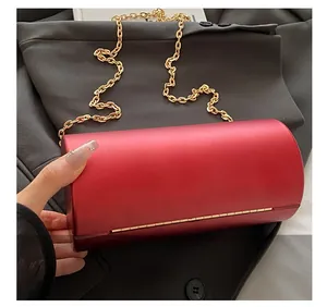 Détail de la pochette cylindrique en velours rouge avec chaîne dorée et fermoir