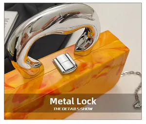 Detail of orange marble acrylic handbag with silver hardware clasp and chunky handle