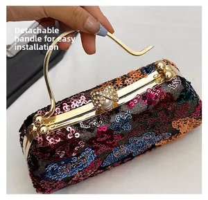 Detail of the detachable gold S-shaped handle on the sequined evening clutch bag