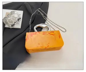 Detailed top view of orange marble acrylic evening bag with silver metal handle and chain