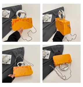 Macro view of orange marble acrylic clutch bag featuring a liquid metal silver handle