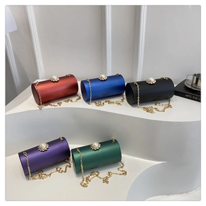 Détail de sacs de soirée cylindriques en satin avec fermoir perle et chaîne dorée