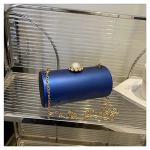 Détail du sac de soirée cylindrique bleu roi avec fermoir perle et chaîne dorée
