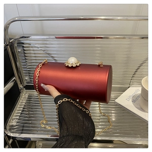 Détail de la pochette cylindrique bordeaux avec fermoir perle et bandoulière chaîne