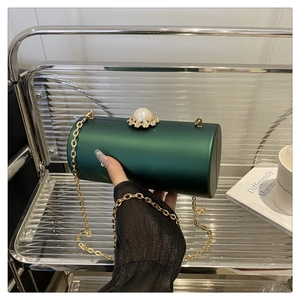 Détail du sac de soirée cylindrique vert foncé avec fermoir perle et chaîne dorée