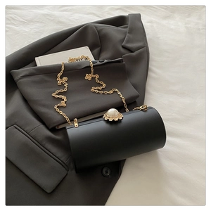 Détail du sac de soirée cylindrique noir avec fermoir perle fleurie et chaîne dorée