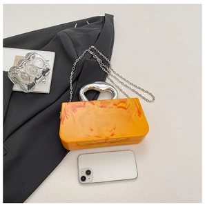 Detail of amber acrylic clutch showing its marble texture and smartphone capacity
