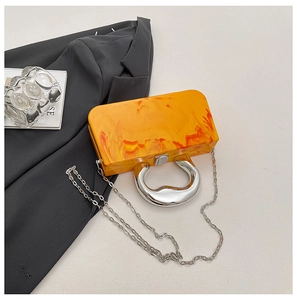 Detailed view of orange marble acrylic evening bag with silver metal ring handle and chain