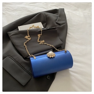 Détail d'un sac cylindre bleu roi avec fermoir perle fleurie et bandoulière chaîne dorée