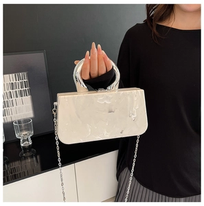 Macro view of marble texture acrylic clutch bag with silver U-shaped metal handle