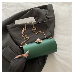Détail du sac de soirée cylindrique en satin vert avec fermoir perle et chaîne dorée