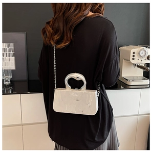 Detail of marble pattern acrylic box bag with silver metal handle and chain strap