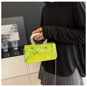 Close-up of marble acrylic clutch with silver U-shaped handle and metallic chain