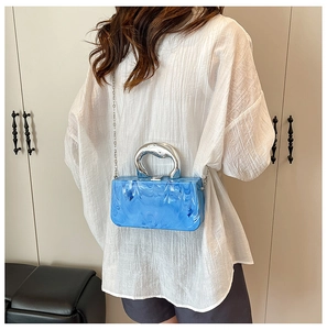 Blue marble acrylic box clutch featuring silver metal top handle and chain strap on model
