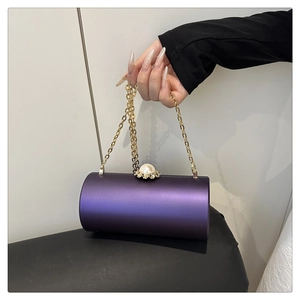 Détail d'un sac de soirée cylindrique violet avec fermoir perle et chaîne dorée fine