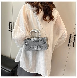 Detail of acrylic marble clutch bag with silver metal handle and chain strap on shoulder