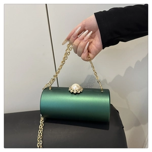 Gros plan d'un sac cylindrique en satin vert avec fermoir floral en perles et strass