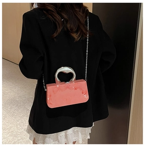 Detailed shot of pink marble acrylic box bag with silver metal ring handle and chain strap