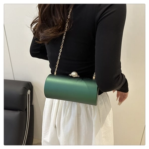 Détail du sac de soirée cylindre vert foncé avec chaîne dorée et grand fermoir perle