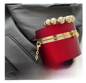 Detalle de bolso de noche rojo cilíndrico con asa de cuentas doradas y gancho