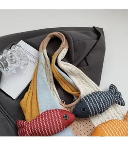 Detail of color-block knit tote bag with decorative fish charms and wide shoulder strap